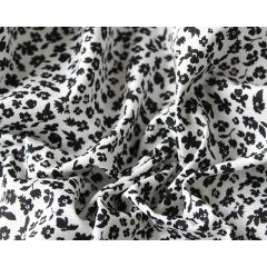 White fabric with a tiny black floral print gathered into soft folds.