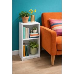 A cozy living room scene with a vibrant orange armchair and a white bookshelf. The shelf holds books and potted plants, set against a teal wall.