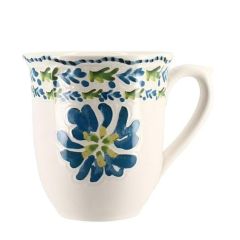 White ceramic mug with a blue floral design and green accents near the rim, featuring a large blue flower on the side.