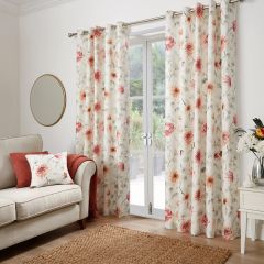 Red floral eyelet curtains with a matching cushion styled in a bright living room.