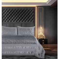 Luxurious bedroom with a tufted black headboard, elegant bedding, and a modern nightstand with a hanging light and decorative items.
