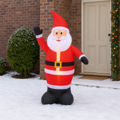 130cm Airpower Inflatable Santa decoration standing in a snowy front garden during daytime, glowing with built-in LED lights beside a decorated house