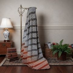 Aztec wave throw with grey, white and rust patterns draped over a decorative stand.