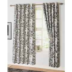 Floral curtains with a leaf pattern hang over a sunlit window. One curtain is partially pulled back, revealing a decorative frame on the windowsill.