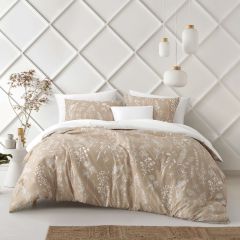 Beige comforter set with delicate white floral designs and a solid white reverse, styled in a bright modern bedroom.