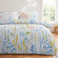 White botanical duvet cover set with blue, green and yellow wildflower print, styled on a bed in a bright, modern bedroom.