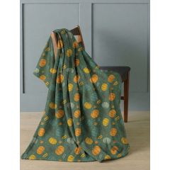 A green pumpkin-print blanket draped over a wooden chair.