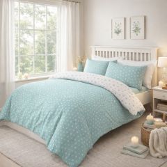Bedroom with a white wooden bed, featuring duck egg and white floral bedding, two matching pillows, and a vase on the bedside table.