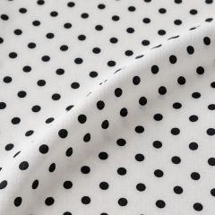 Close-up of white georgette fabric covered in evenly spaced black polka dots.