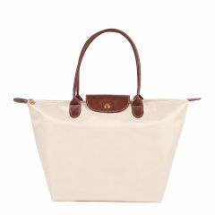 A stylish cream tote bag with brown leather handles and a flap. It features a gold button closure, exuding a classic and elegant appeal.