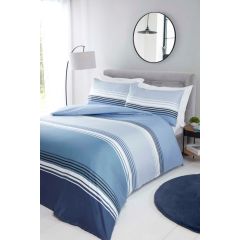 Modern bedroom with a bed featuring blue striped bedding, a round mirror, floor lamp, and a small side table with a plant.