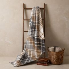Dunmore check throw in soft beige, grey and cream tones draped over a wooden ladder.