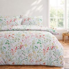 White floral duvet cover set with a delicate multicoloured botanical print, styled on a bed in a bright, modern bedroom.