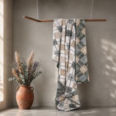 Fern check throw in soft green, beige and white tones draped over a wooden rail.