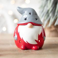 Festive gnome wax melt burner displayed on wooden surface with fairy lights in background