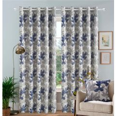 Floral patterned jacquard curtains in navy and gray hang in a cozy living room. A beige armchair with a matching cushion, houseplant, and floor lamp complete the decor.