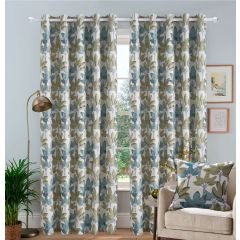 Floral patterned jacquard curtains in olive green and turquoise hang in a cozy living room. A beige armchair with a matching cushion, houseplant, and floor lamp complete the decor.