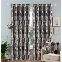 Elegant living room with geo patterned curtains in neutral tones, matching cushion on beige sofa, a brass floor lamp, and framed art on pale blue walls. Cozy ambiance.