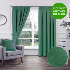 Green soft touch blockout pencil pleat curtains styled in a bright modern living room with grey armchair