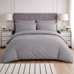 Grey duvet cover set on upholstered bed with matching pillows in a bright modern bedroom