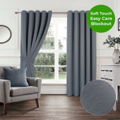 Grey soft touch blockout eyelet curtains styled in a modern living room with grey armchair