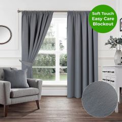 Grey soft touch blockout pencil pleat curtains styled in a bright modern living room with grey armchair