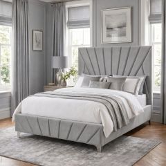 Grey upholstered bed frame with tall geometric fan-panel headboard and matching footboard in a modern bedroom.