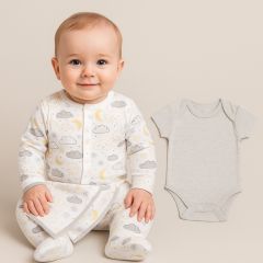 Baby boy wearing a 100% cotton grey and white sleepsuit with yellow cloud and moon print, sitting on a neutral background with a matching grey bodysuit beside him.