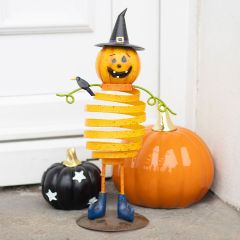 Spiral pumpkin figure with a witch hat and a crow, standing between two pumpkins by a door.