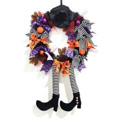 Halloween wreath with witch hat and dangling striped legs, decorated with orange, purple, and black bows for festive front door decoration