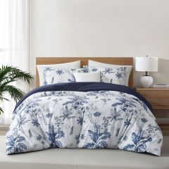 White comforter set with navy floral designs and a solid navy reverse, styled in a bright bedroom.