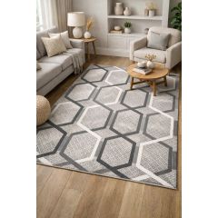 Cozy living room with a geometric-patterned rug in shades of gray. Neutral sofas, armchairs, and warm wooden furniture create an inviting atmosphere.