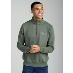 Smiling person wearing an khaki quarter-zip sweatshirt with an embroidered logo, hands clasped, and blue jeans, against a gray background.