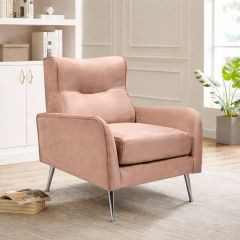 Modern grey velvet armchair with chrome legs in a bright living room setting, styled beside a floor lamp and side table.