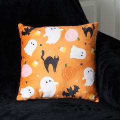 Orange pillow with Halloween-themed designs: white ghosts, black cats, bats, pumpkins, and candy corn, set against a black background.