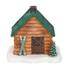 Front view of log cabin incense cone burner with green roof and skis leaning against the wall