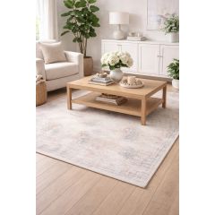 Stylish living room with a cozy armchair, a wooden coffee table, and a white sideboard. Soft, patterned pink-and-cream rug and plants add a serene, inviting tone.