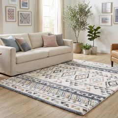 Cream geometric area rug with blue, beige and blush pattern in a bright modern living room.