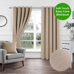 Natural beige soft touch blockout eyelet curtains styled in a modern living room with grey armchair