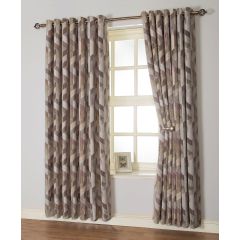 Geometric-patterned curtains in muted tones cover a window, with one side tied back. A small framed photo sits on the sill. The room feels cozy.