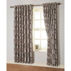 Taupe geometric-patterned curtains hang over a window with light streaming through. A small framed picture rests on the windowsill below.