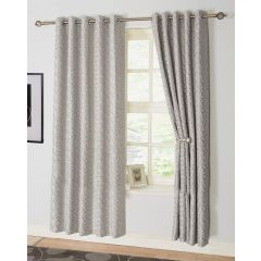 Gray textured curtains hang on a rod over a window, with one side tied back to reveal light streaming in. The ambiance is serene and elegant.