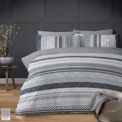 A chic bedroom scene with a gray and white Peruvian Stripe bedding set featuring geometric patterns, set against a dark paneled wall, and a vase of branches on a side table.