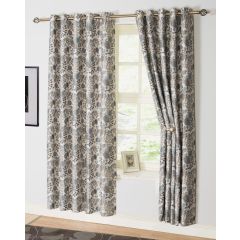 Floral-patterned curtains in beige, gray, and blue partially cover a window. Light filters through, illuminating a small framed picture on the sill. Cozy and elegant ambiance.