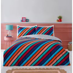 A bed with vibrant diagonal striped bedding in blue, red, and orange. A turquoise lamp and small framed pictures adorn the pink wall.
