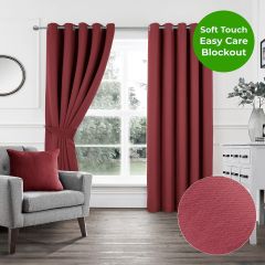 Red soft touch blockout eyelet curtains in a modern living room with grey armchair