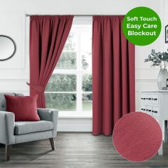 Red soft touch blockout pencil pleat curtains styled in a bright modern living room with grey armchair