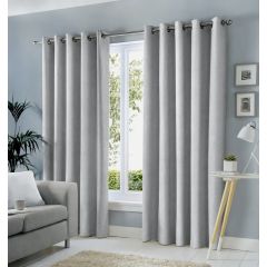 Silver-grey Sorbonne eyelet curtains framing a window in a bright, modern living room.