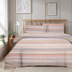 A neatly made bed with a striped duvet in earthy tones, two matching pillows, wooden headboard, and modern wall art in a bright room.