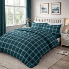 A neatly made bed with teal and white plaid bedding, white wooden frame, and a vase of flowers on a light wooden floor near a window.